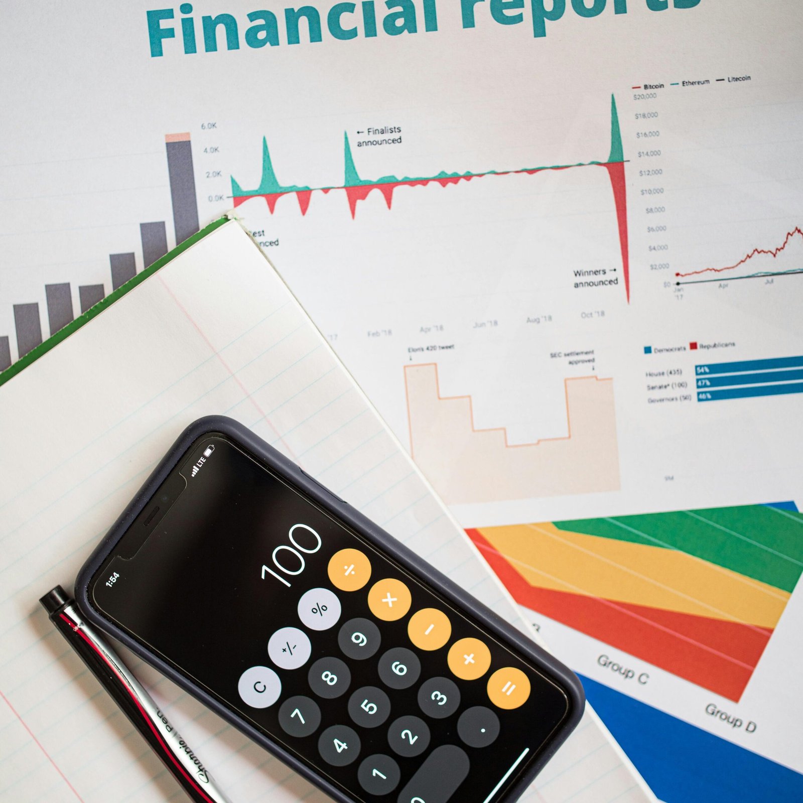 Top view of financial reports with a calculator app open on a smartphone.